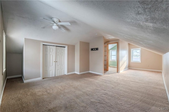 bonus room with ceiling fan, a textured ceiling, light colored carpet, and vaulted ceiling