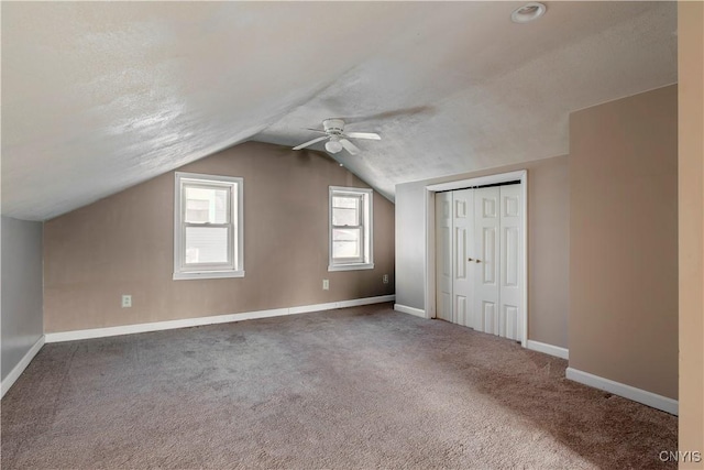 bonus room featuring a textured ceiling, lofted ceiling, carpet, and ceiling fan