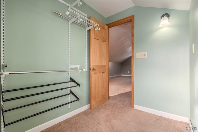 walk in closet with light carpet and vaulted ceiling