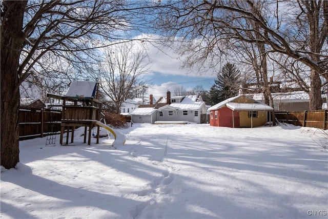 snowy yard featuring a playground and a shed