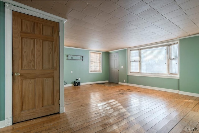 empty room with ornamental molding, plenty of natural light, and light hardwood / wood-style flooring