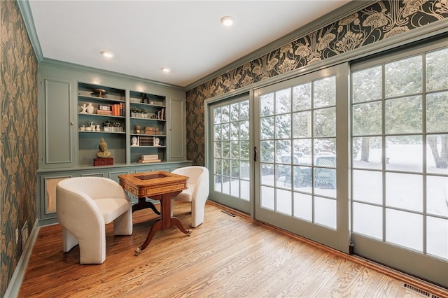 living area with ornamental molding and light wood-type flooring