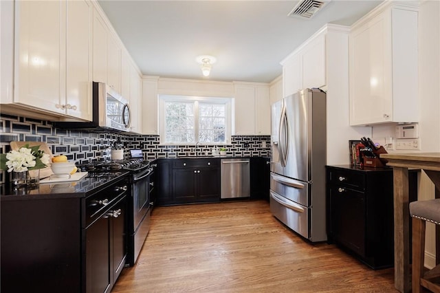 kitchen featuring sink, stainless steel appliances, white cabinets, decorative backsplash, and light wood-type flooring