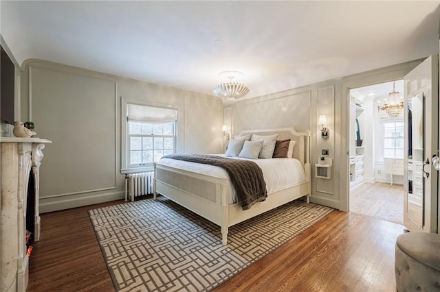 bedroom featuring radiator heating unit, a chandelier, hardwood / wood-style floors, and multiple windows