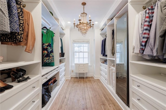 spacious closet with a notable chandelier and light hardwood / wood-style floors