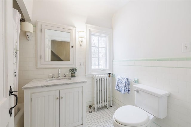 bathroom with radiator heating unit, toilet, tile walls, and vanity