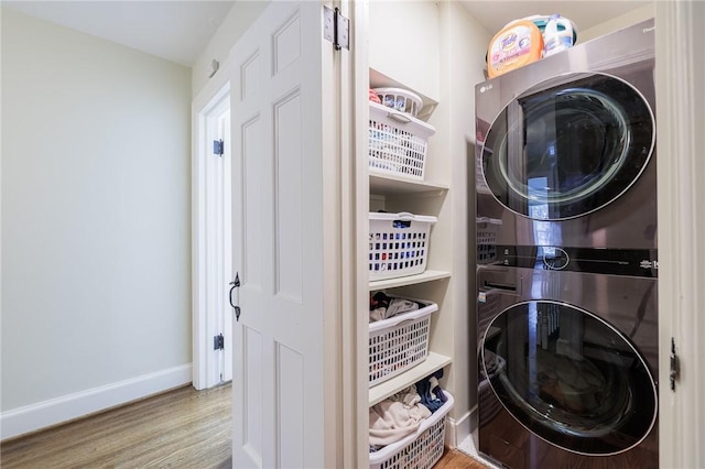 clothes washing area with stacked washer and dryer and wood-type flooring