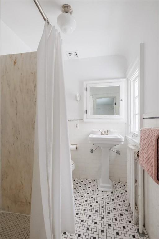 bathroom featuring tile walls, radiator heating unit, curtained shower, tile patterned floors, and toilet