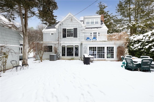 snow covered back of property featuring cooling unit and a balcony