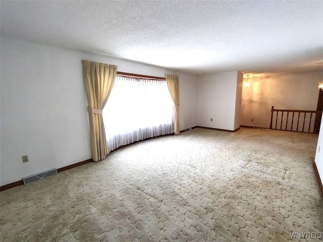 carpeted spare room with a textured ceiling