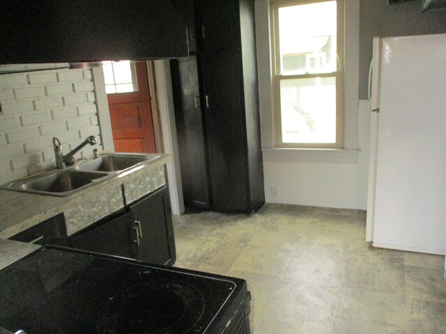 kitchen with a healthy amount of sunlight, white fridge, sink, and black / electric stove