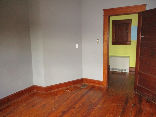 spare room featuring dark wood-type flooring and radiator