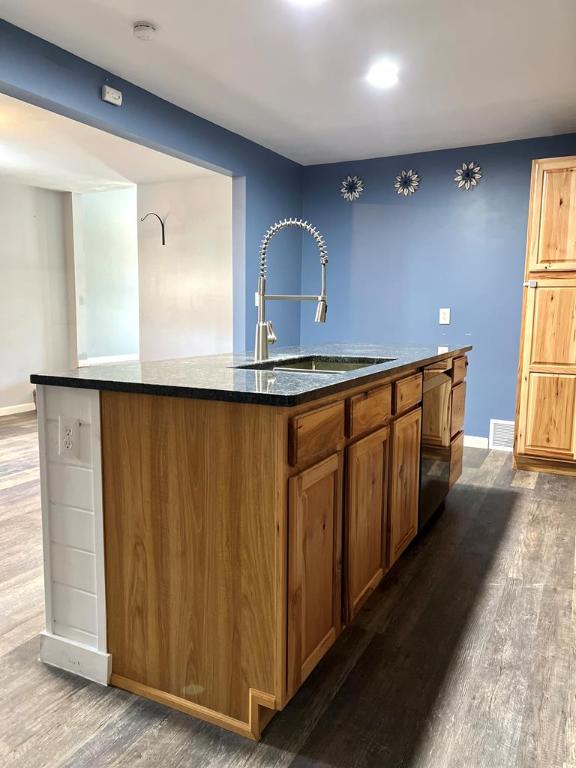 576 W High St, Erwin, NY 14870 - kitchen featuring wood finished floors, brown cabinetry, a sink, baseboards, and a center island with sink
