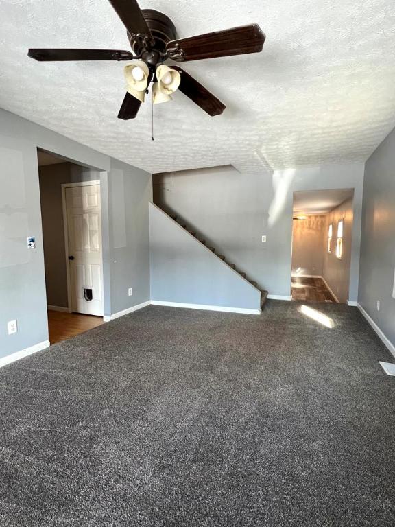 empty room featuring a textured ceiling and dark colored carpet