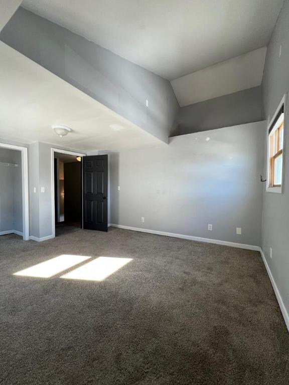 carpeted spare room featuring vaulted ceiling