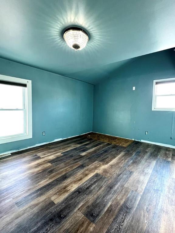 spare room featuring lofted ceiling and dark hardwood / wood-style floors