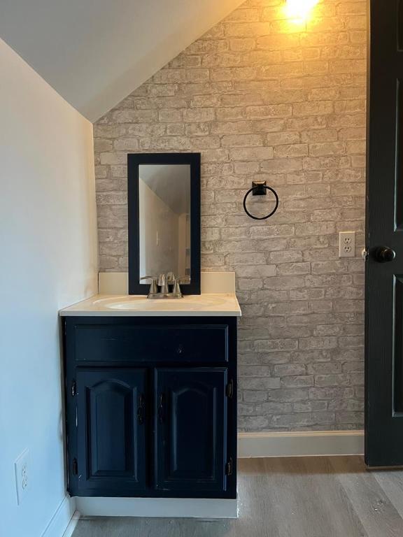 bathroom with vanity, vaulted ceiling, and wood-type flooring