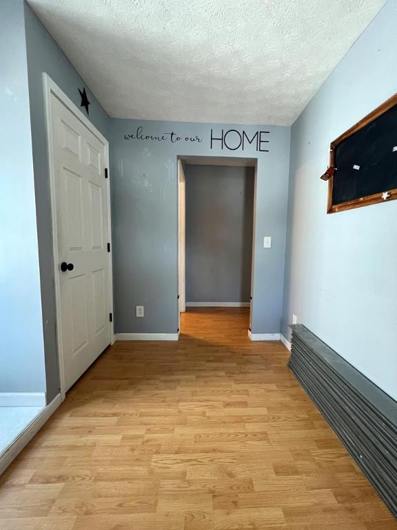 unfurnished room with a textured ceiling and light hardwood / wood-style floors