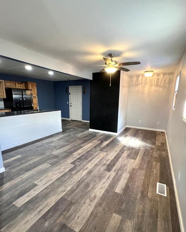 unfurnished living room featuring dark hardwood / wood-style floors, sink, and ceiling fan