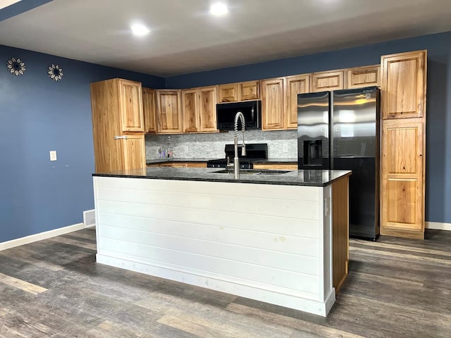 kitchen featuring stainless steel refrigerator with ice dispenser, dark wood-type flooring, sink, tasteful backsplash, and a kitchen island with sink