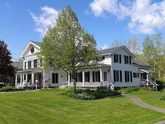 rear view of property featuring a porch and a lawn