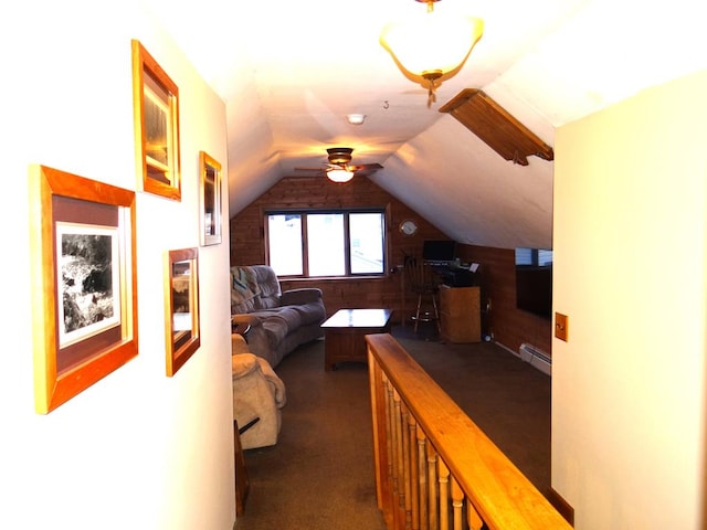 corridor with a baseboard radiator, vaulted ceiling, and dark colored carpet