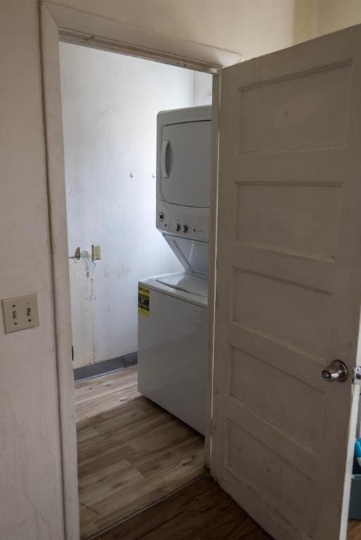 clothes washing area with wood-type flooring and stacked washer and clothes dryer