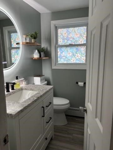 bathroom with vanity, a baseboard heating unit, hardwood / wood-style floors, and toilet