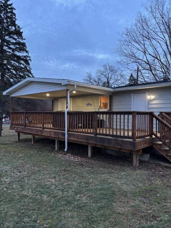 rear view of property with a wooden deck and a lawn