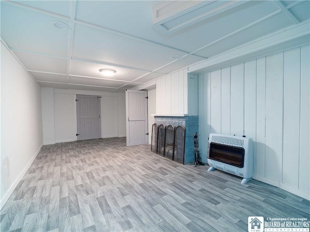 basement with heating unit, a brick fireplace, and light hardwood / wood-style flooring