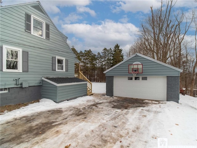 snow covered property featuring an outbuilding and a garage