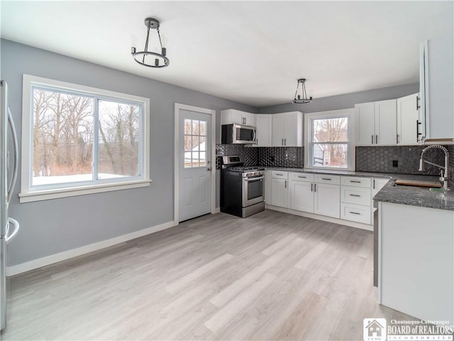 kitchen with pendant lighting, sink, white cabinetry, and stainless steel appliances