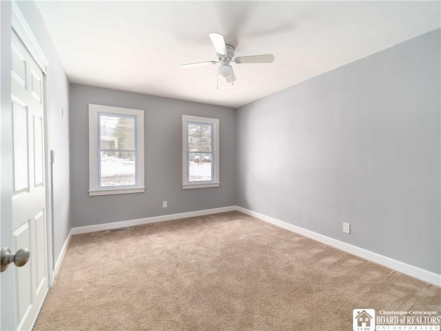 empty room featuring ceiling fan and light carpet