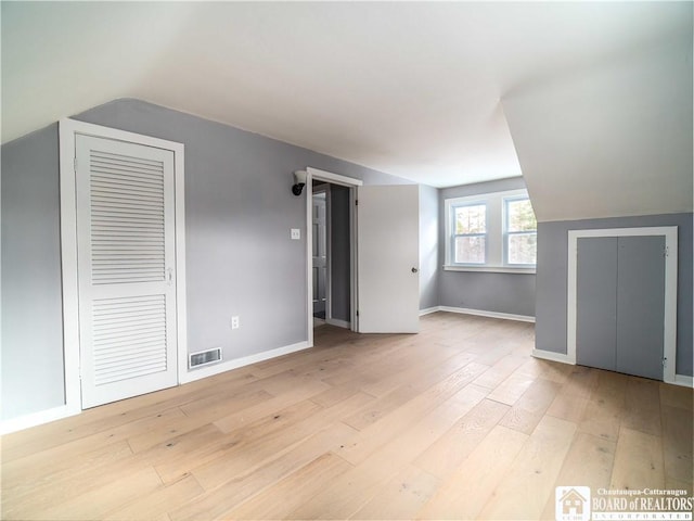 bonus room with vaulted ceiling and light wood-type flooring