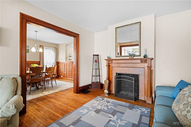 living room with wood-type flooring, a fireplace, and a notable chandelier