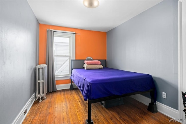 bedroom with hardwood / wood-style flooring and radiator heating unit