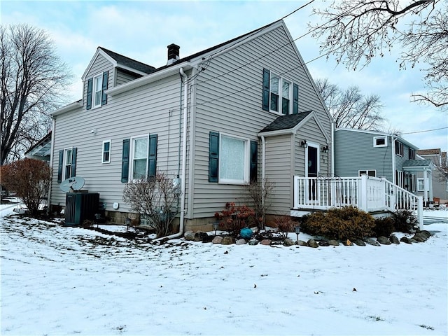 snow covered house with a wooden deck and central air condition unit