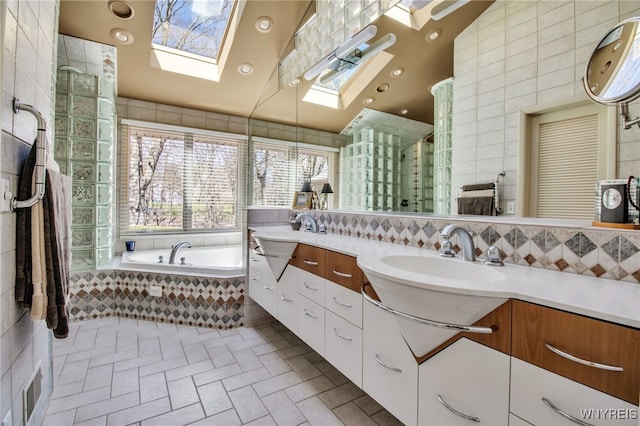 bathroom with tiled bath, vanity, tile walls, and a skylight