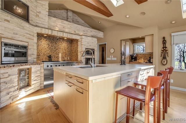 kitchen featuring sink, backsplash, oven, and an island with sink