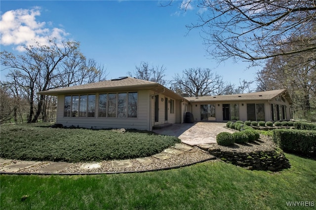 rear view of property featuring a patio area and a lawn