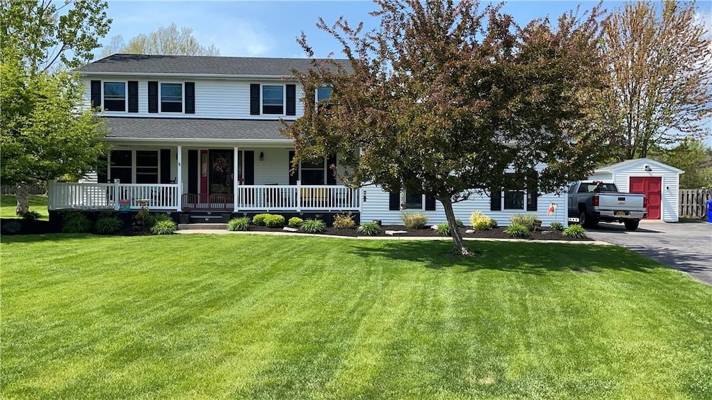 view of front of home with a front yard, covered porch, and a shed