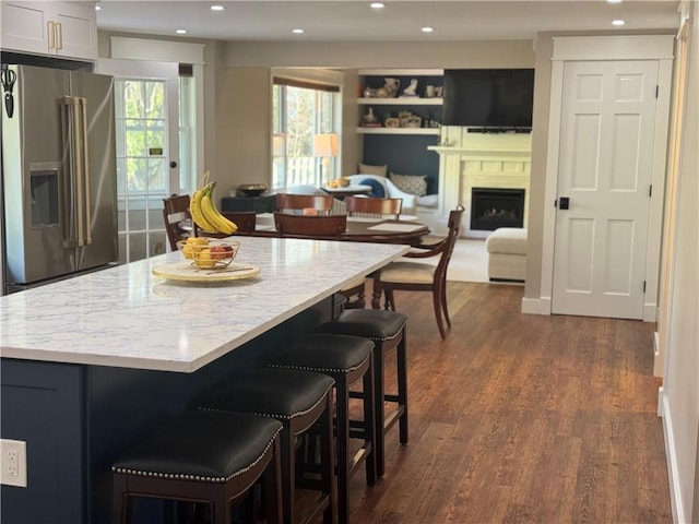 kitchen with a breakfast bar area, dark hardwood / wood-style floors, a center island, white cabinets, and high end refrigerator