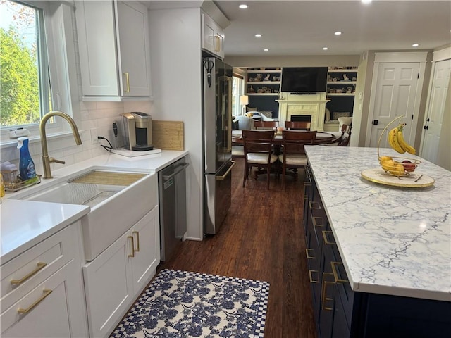 kitchen featuring dark hardwood / wood-style floors, sink, white cabinets, decorative backsplash, and stainless steel appliances