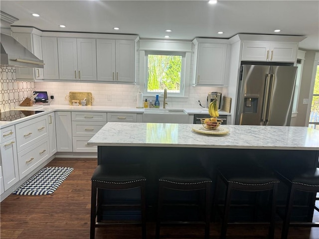 kitchen with white cabinetry, high quality fridge, a kitchen breakfast bar, and sink