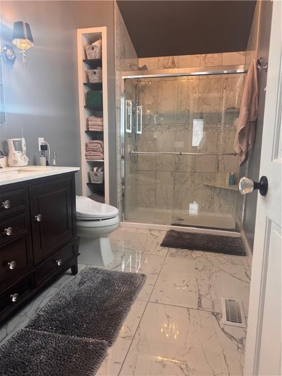 bathroom featuring vanity, a shower with door, and toilet