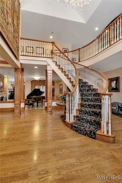 staircase with a towering ceiling, hardwood / wood-style floors, and ornate columns