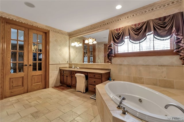 bathroom with french doors, vanity, tiled bath, and tile walls