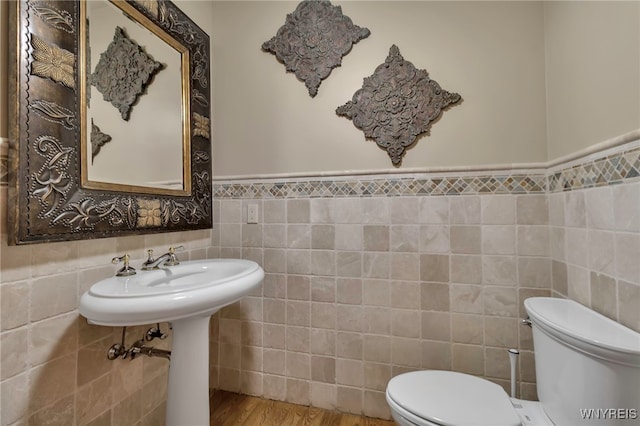 bathroom with tile walls, hardwood / wood-style flooring, and toilet