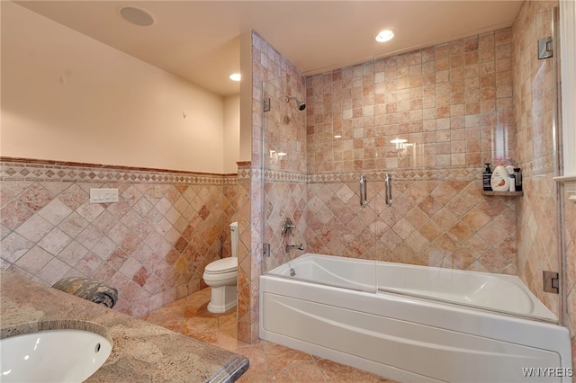 full bathroom featuring tile walls, tile patterned flooring, tiled shower / bath combo, vanity, and toilet