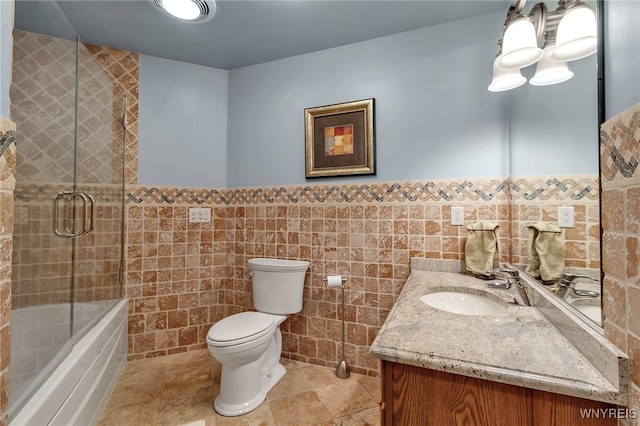 full bathroom featuring vanity, tile walls, enclosed tub / shower combo, and toilet